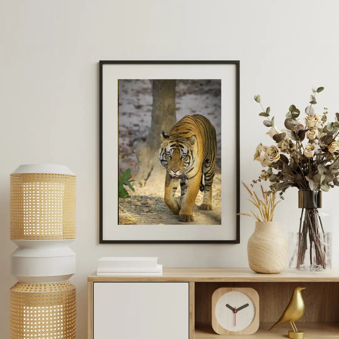 Framed picture of a tiger on a wall above a wooden console table with decorative items.