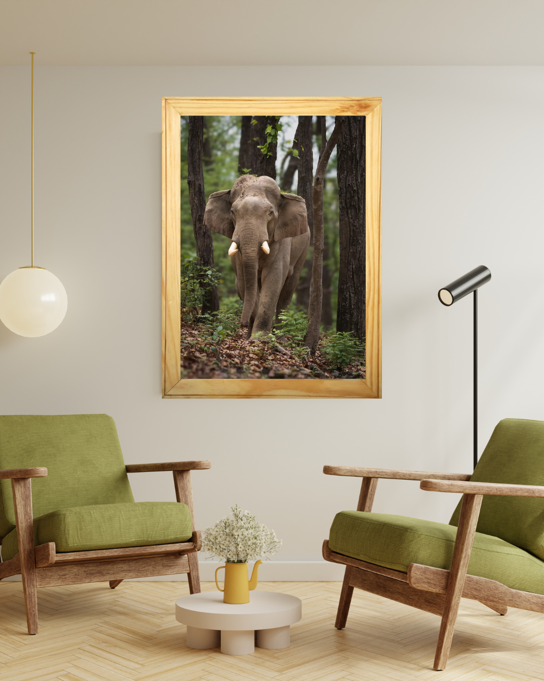 A framed vertical art print of an elephant walking through a dense forest, displayed on a light gray wall in a modern living room setting with two green armchairs and a small round coffee table.